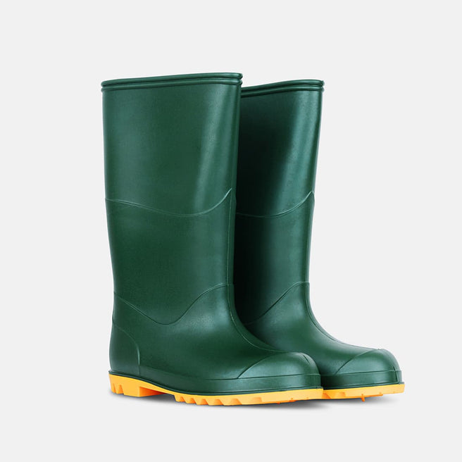 A pair of green 'Classic Wellies' stand on a white surface, their bright orange soles providing a vibrant contrast.